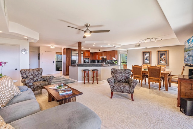 living room featuring ceiling fan, light colored carpet, and sink