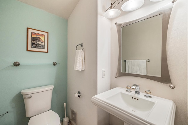 bathroom with toilet, lofted ceiling, and sink