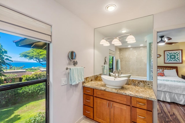 bathroom with hardwood / wood-style floors, vanity, ceiling fan, and tiled shower