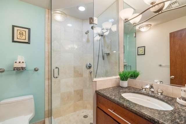 bathroom with vanity, toilet, and a shower with door