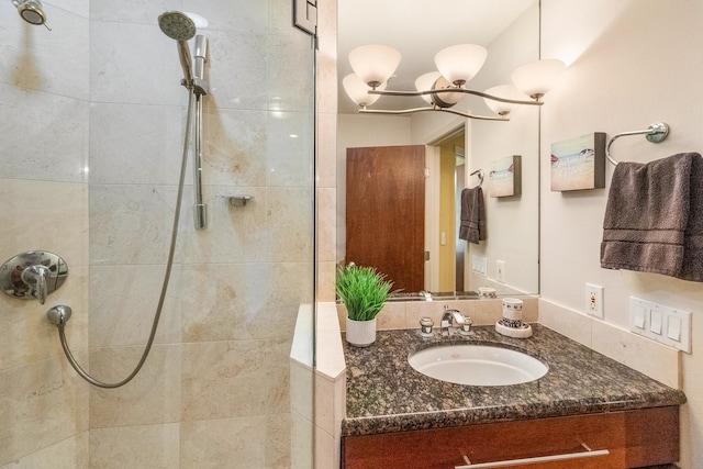 bathroom featuring a notable chandelier, vanity, and tiled shower