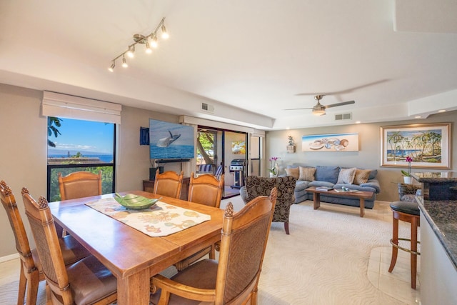 dining space with ceiling fan and light carpet