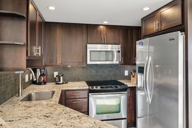 kitchen featuring light stone counters, a sink, tasteful backsplash, stainless steel appliances, and dark brown cabinets