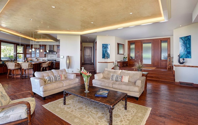 living room with dark wood-type flooring and a tray ceiling