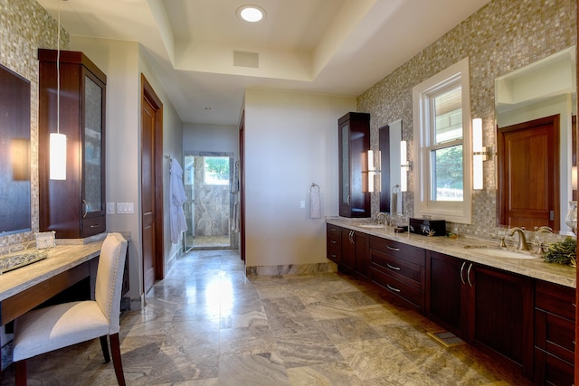 bathroom featuring a tray ceiling, tile floors, vanity with extensive cabinet space, and a wealth of natural light