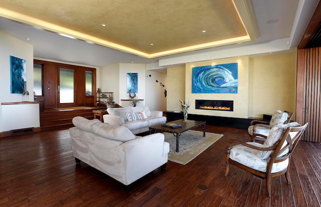 living room with dark hardwood / wood-style floors and a raised ceiling