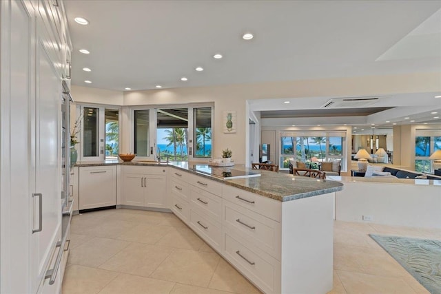 kitchen with white cabinets, dark stone countertops, black electric stovetop, sink, and light tile patterned floors