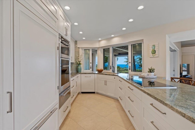 kitchen featuring white cabinetry, sink, light stone countertops, light tile patterned floors, and black electric stovetop