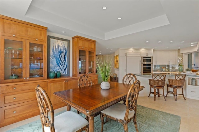 dining room featuring a tray ceiling and light tile patterned floors