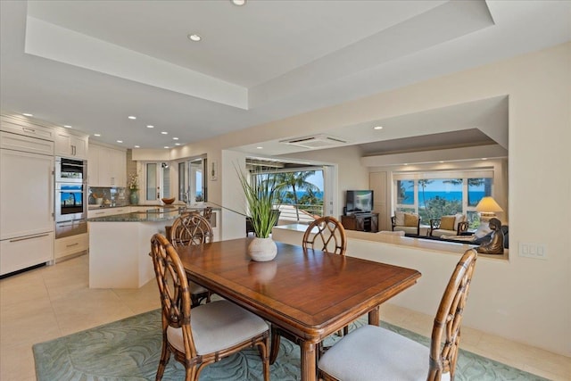 dining area with a tray ceiling and light tile patterned floors