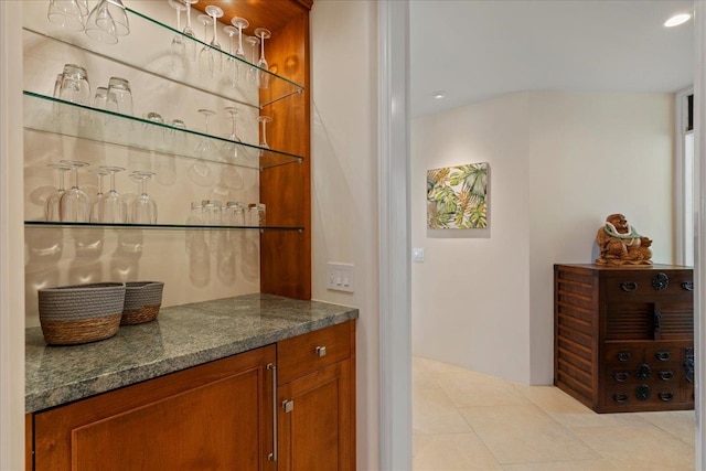 bar featuring dark stone counters and light tile patterned floors