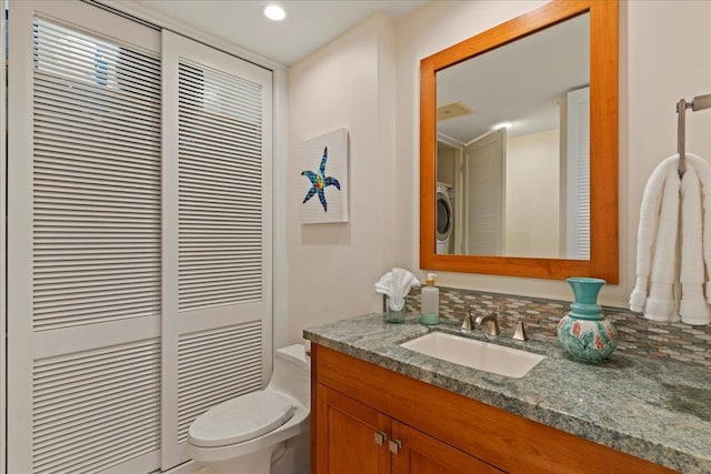 bathroom featuring washer / dryer, toilet, and vanity