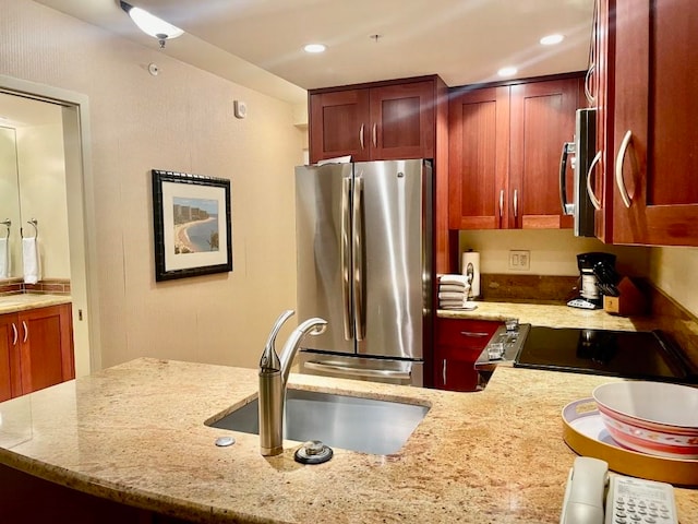 kitchen featuring light stone counters, stainless steel appliances, and sink