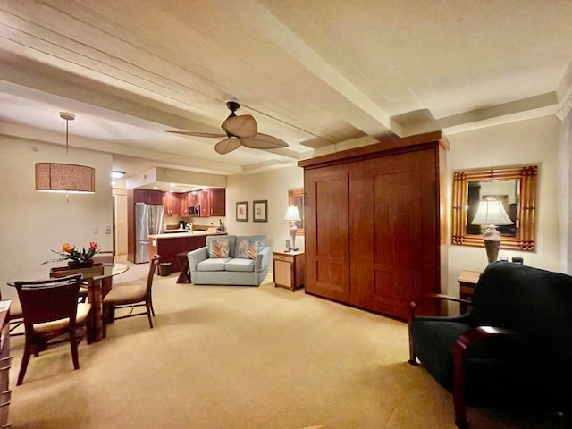 sitting room featuring beamed ceiling, light carpet, and ceiling fan