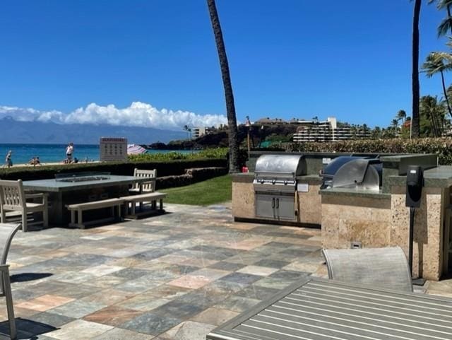 view of patio with area for grilling, grilling area, and a water view