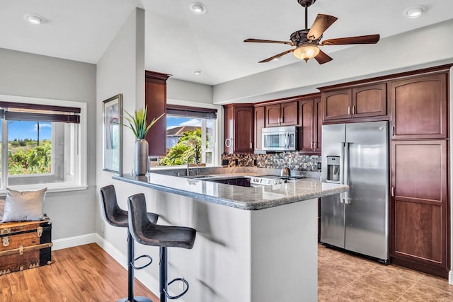 207 Kahana Ridge Dr Unit 132, Lahaina, HI 96761 - kitchen with stainless steel appliances, a sink, baseboards, a kitchen bar, and tasteful backsplash
