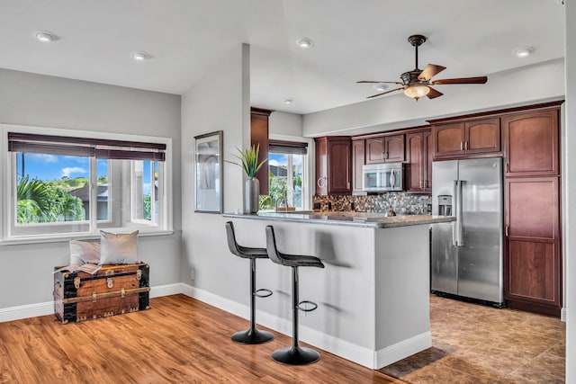 207 Kahana Ridge Dr Unit 132, Lahaina, HI 96761 - kitchen featuring appliances with stainless steel finishes, a ceiling fan, a peninsula, a kitchen breakfast bar, and tasteful backsplash