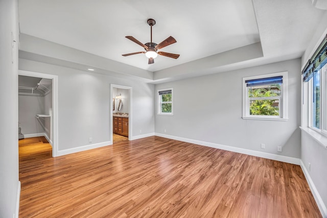 207 Kahana Ridge Dr Unit 132, Lahaina, HI 96761 - unfurnished bedroom with light wood-type flooring, baseboards, a tray ceiling, and a walk in closet