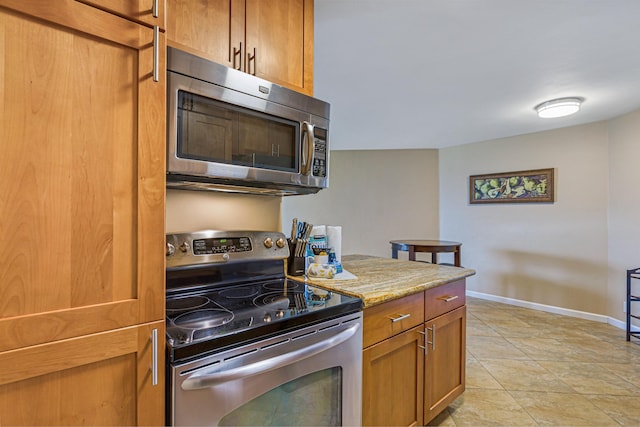 kitchen with light stone countertops, appliances with stainless steel finishes, and light tile patterned flooring