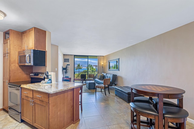 kitchen featuring floor to ceiling windows, light tile patterned flooring, light stone countertops, and stainless steel appliances