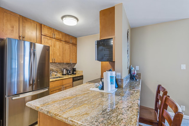 kitchen with decorative backsplash, sink, light stone counters, and stainless steel appliances