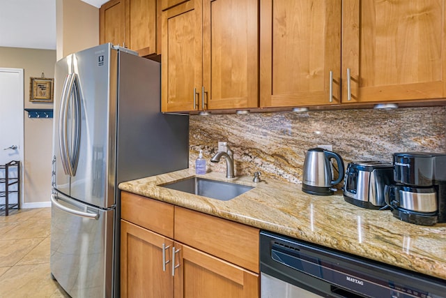 kitchen featuring appliances with stainless steel finishes, backsplash, light stone counters, sink, and light tile patterned floors