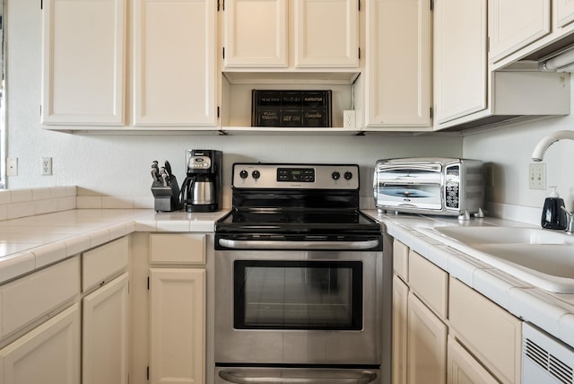 kitchen with sink, tile counters, and stainless steel electric range