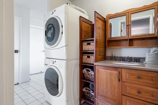 laundry room featuring cabinets, light tile patterned floors, stacked washer / dryer, and sink