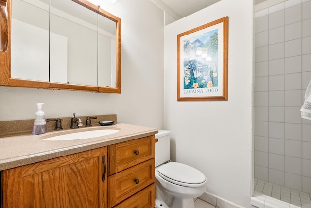 bathroom with a tile shower, vanity, and toilet