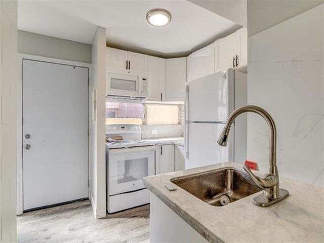 kitchen featuring white cabinetry, white appliances, sink, and light hardwood / wood-style flooring