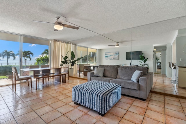 tiled living room featuring ceiling fan, expansive windows, and a textured ceiling