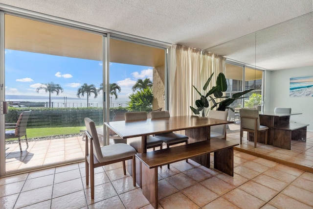 dining space featuring expansive windows, a textured ceiling, a water view, and tile patterned floors