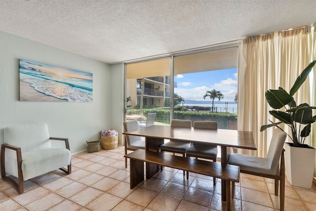 dining area with a water view, tile patterned floors, and a textured ceiling