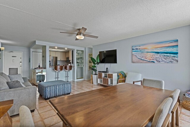 tiled dining space with ceiling fan and a textured ceiling