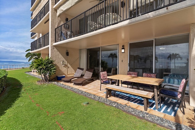 rear view of house with a water view, a patio, a yard, and a balcony