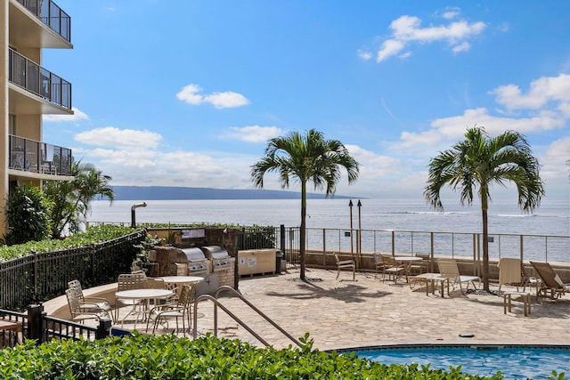 exterior space featuring a water view, a grill, a balcony, and a community pool