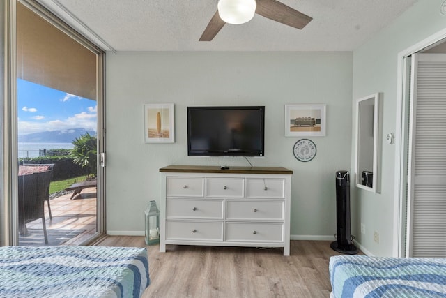 bedroom with ceiling fan, a textured ceiling, light hardwood / wood-style flooring, and access to exterior