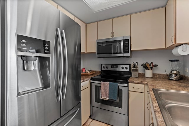 kitchen with cream cabinets, appliances with stainless steel finishes, sink, and light tile patterned floors