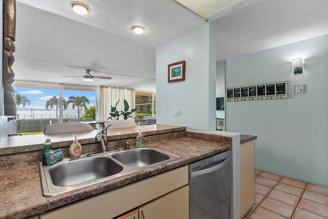 kitchen with dishwasher, sink, light tile patterned floors, and a textured ceiling