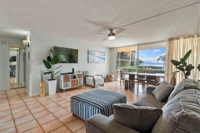 living room featuring ceiling fan, a textured ceiling, expansive windows, and light tile patterned flooring