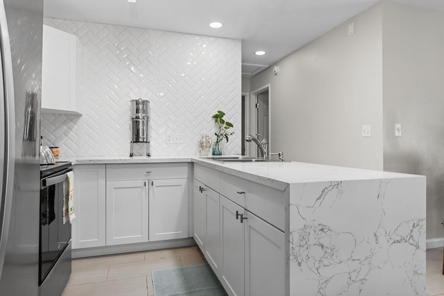 kitchen with a peninsula, electric range, tasteful backsplash, and a sink