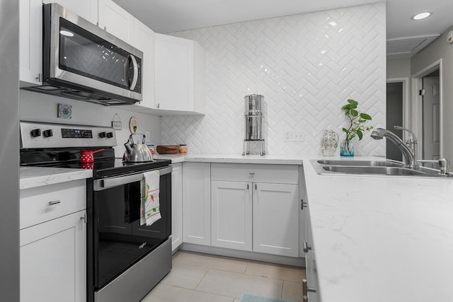 kitchen with tasteful backsplash, white cabinetry, stainless steel appliances, and a sink