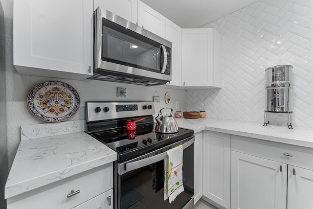 kitchen featuring light stone counters, decorative backsplash, appliances with stainless steel finishes, and white cabinetry