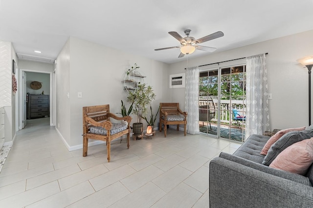 living area with light tile patterned floors, baseboards, a ceiling fan, and a wall unit AC