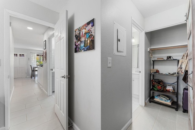 hall with electric panel, light tile patterned flooring, and baseboards