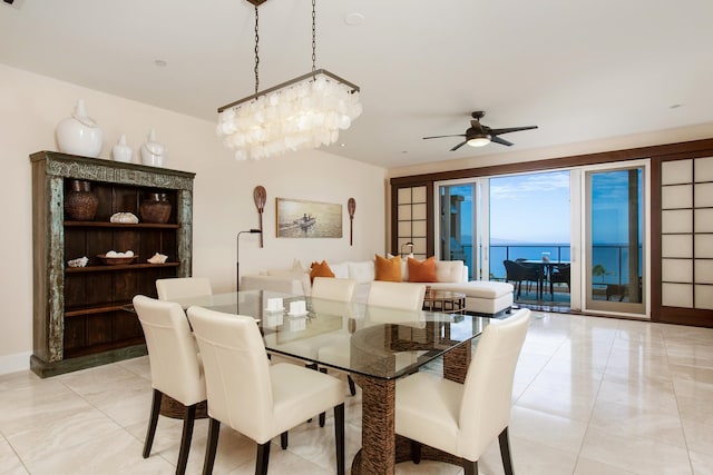 dining area with a water view and ceiling fan with notable chandelier