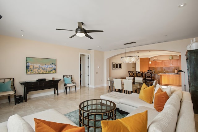 living room featuring sink, light tile patterned flooring, and ceiling fan with notable chandelier