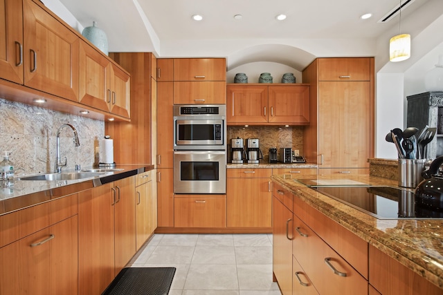 kitchen featuring sink, light stone countertops, stainless steel double oven, black electric stovetop, and decorative backsplash