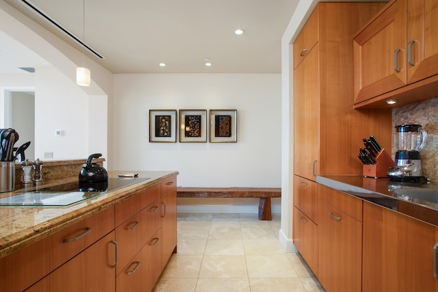 kitchen featuring light stone counters, hanging light fixtures, decorative backsplash, and light tile patterned floors