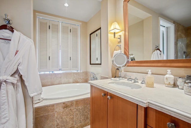 bathroom with vanity and tiled tub